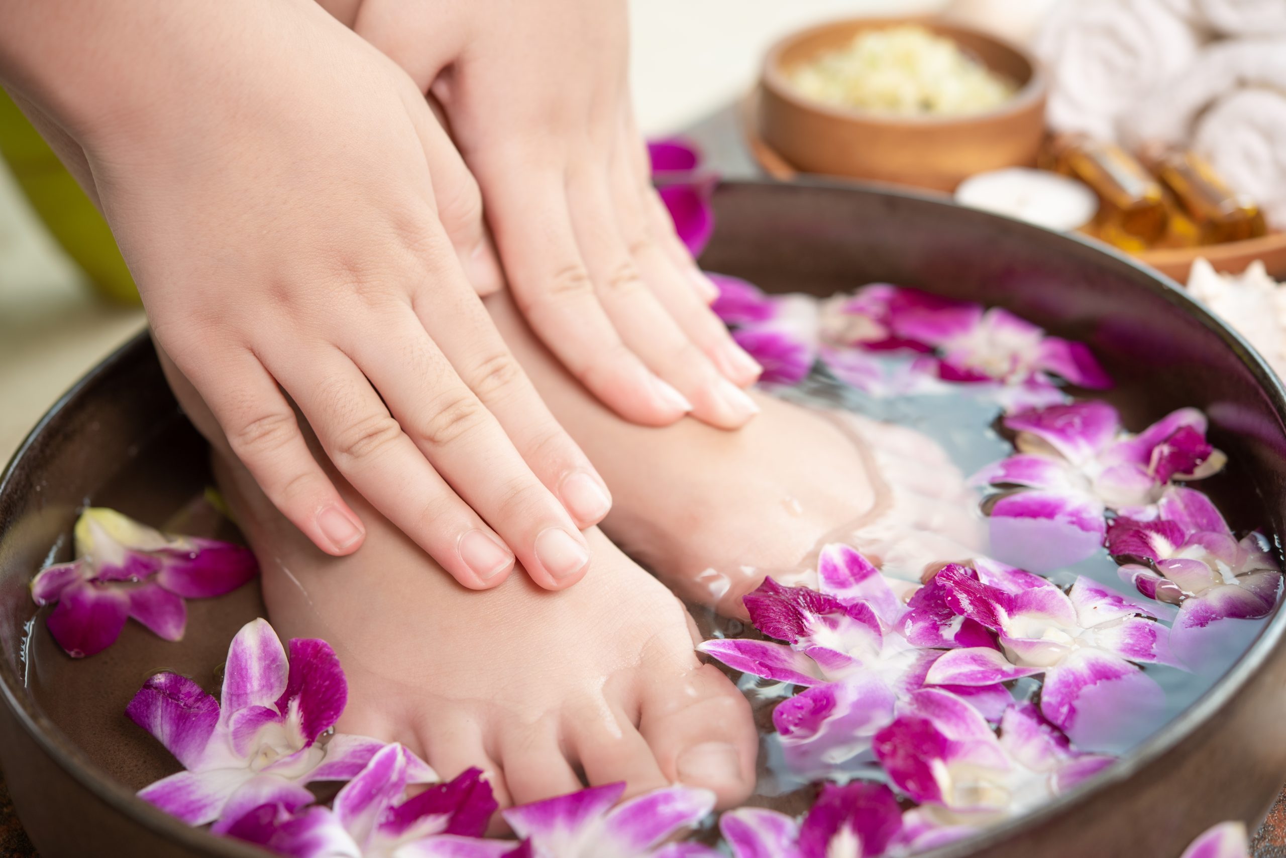 closeup view of woman soaking her hand and feet in dish with wat